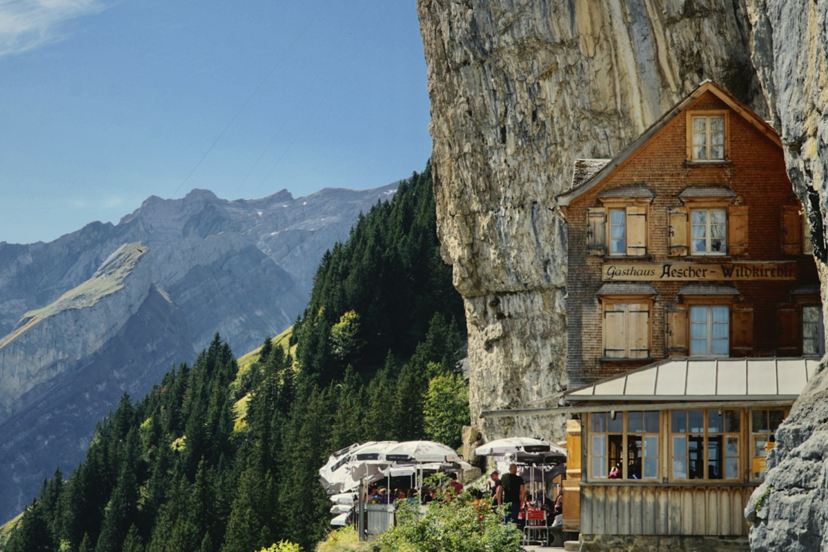 Wooden guesthouse next to a rock in the Swiss Alps.