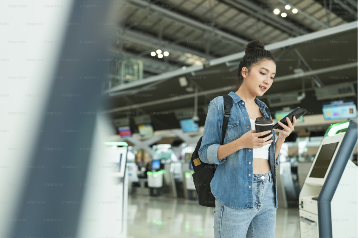 Traveler checking directions on a phone in an airport terminal.