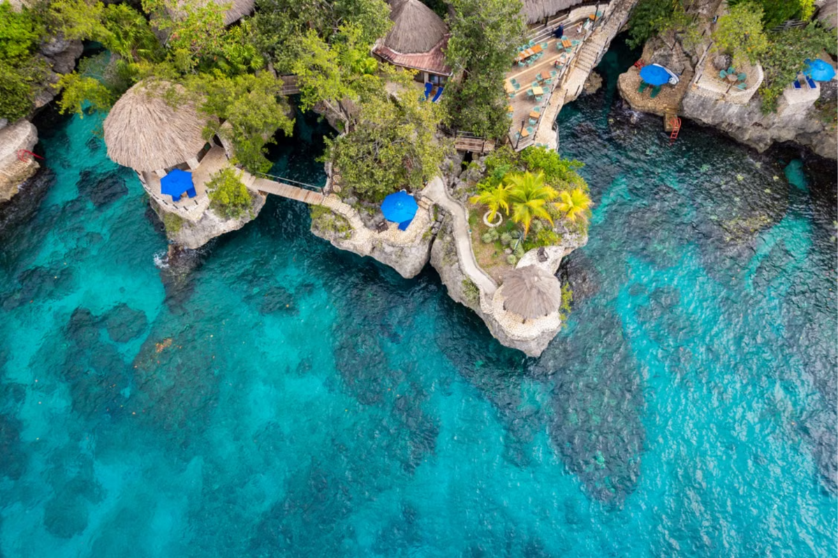 Aerial shot of a Jamaican resort built into the natural rocky landscape overlooking the ocean.